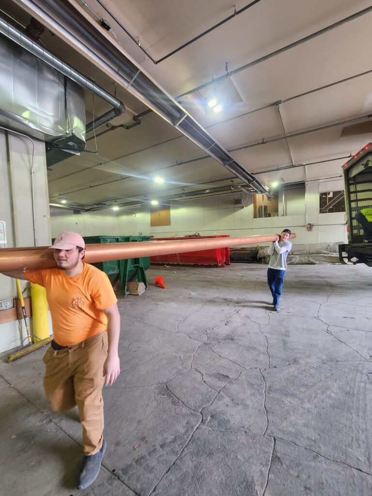 Long Copper Pipe being carried by technicians for New Construction by Mountain Hydronics